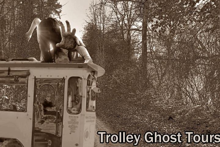 Ghostly figure atop trolley with 'Trolley Ghost Tours' text in wooded area.