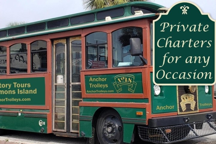 Green tour trolley labeled 'Anchor Trolleys' and sign promoting private charters for any occasion.